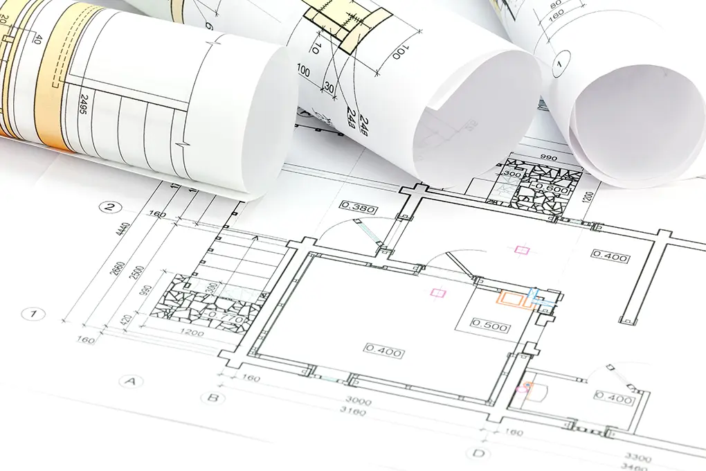 Rolled and flat printed plans laid out for review in a workspace