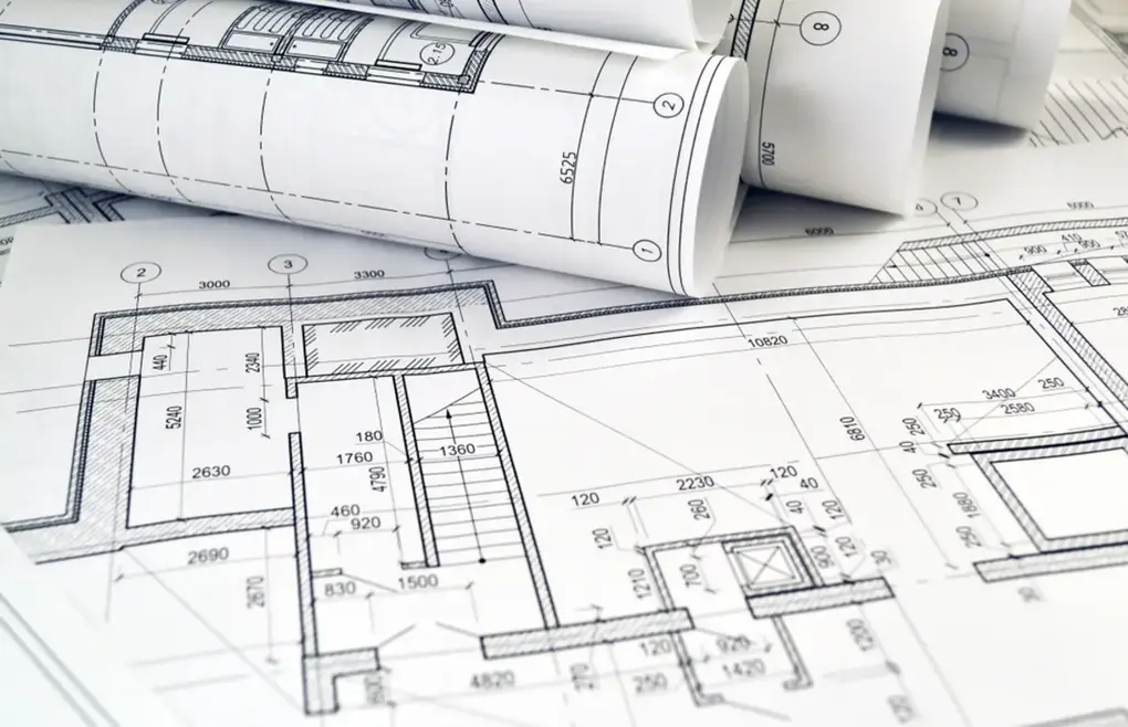 Rolled and flat printed plans laid out for review in a workspace